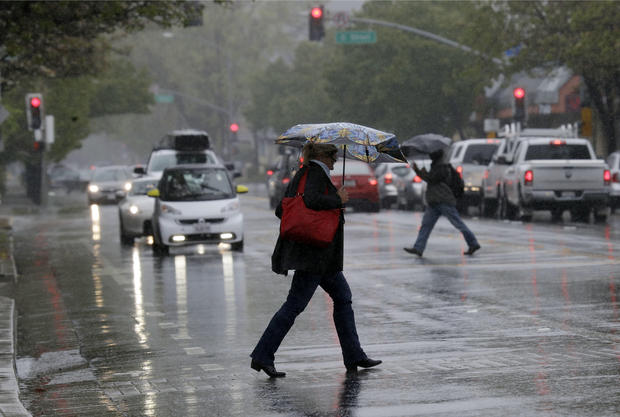 Pedestrians shield themselves from the rain with umbrellas Friday