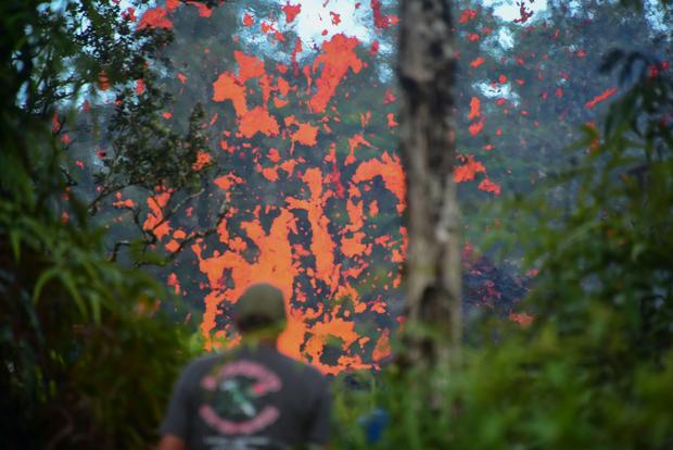 A man watches as lava is seen coming from a fissure in Leilani Estates subdivision on Hawaii's Big Island on May 4