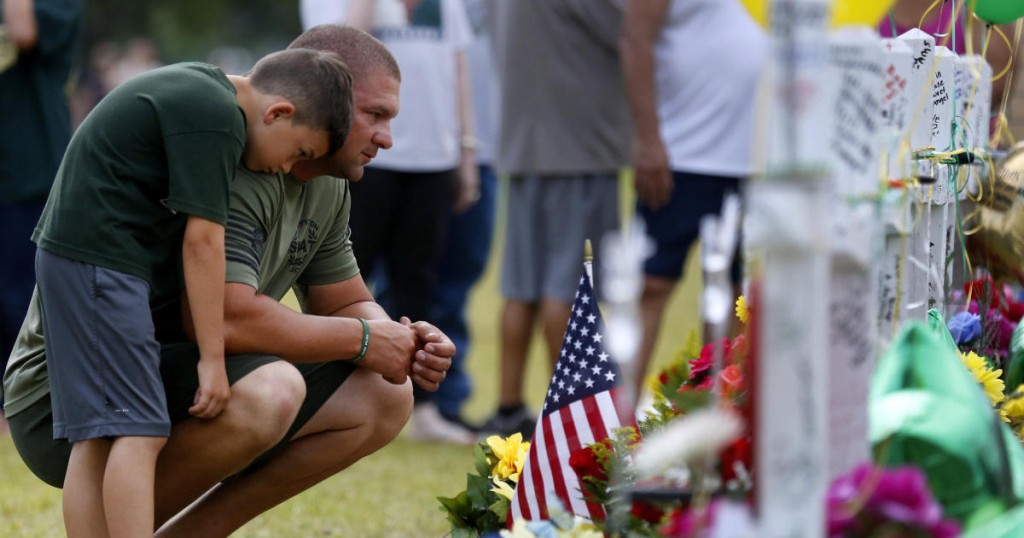 Mourners pray at a makeshift memorial left in memory of the victims killed in a shooting at Santa Fe High School in Santa Fe