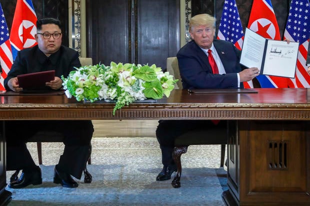 U.S. President Donald Trump holds up the document that he and North Korea leader Kim Jong Un just signed at the Capella resort on Sentosa Island Tuesday