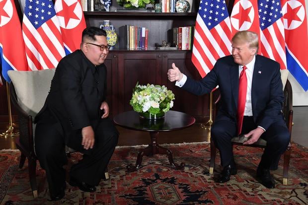 US President Donald Trump (R) gives a thumbs up as he sits down with North Korea's leader Kim Jong Un (L) for their historic US-North Korea summit