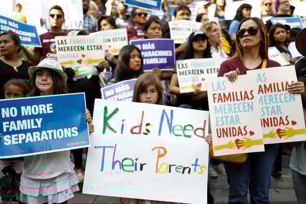 People hold signs to protest against U.S. President Donald Trump's executive order to detain children crossing the southern U.S. border and separating families outside of City Hall in Los Angeles