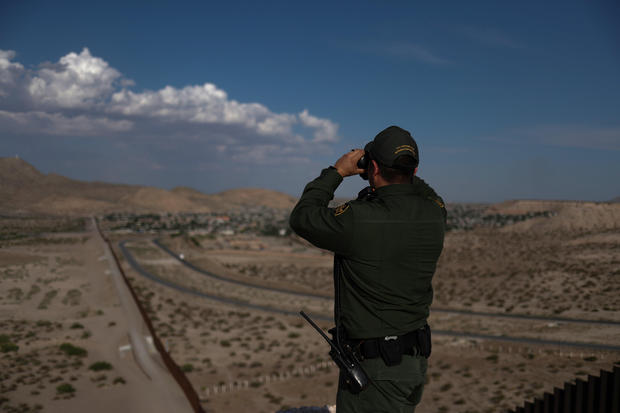 A border patrol agent uses binoculars while searching for illegal immigrants along the U.S. border with Mexico in Sunland Park
