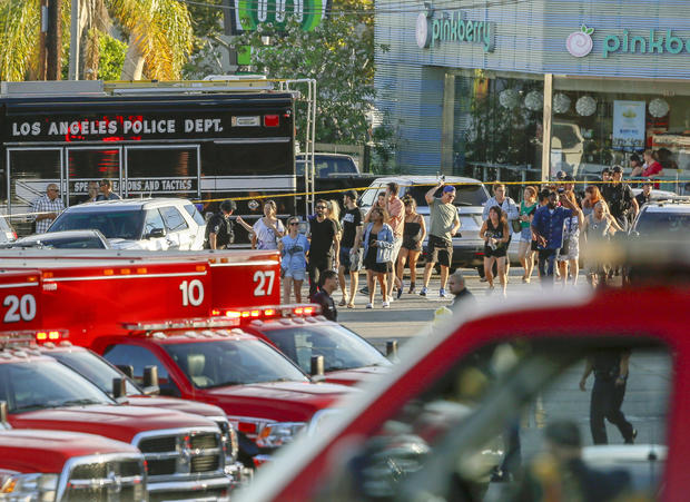 Los Angeles Police SWAT officers escort a group of people who were held for their safety by police across businesses surrounding a Trader Joe's supermarket