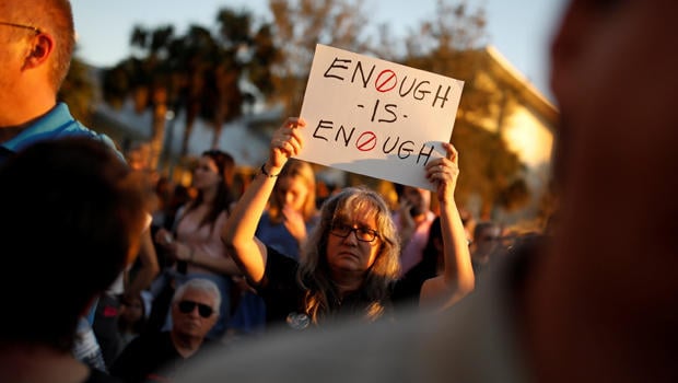 A woman holds a placard during a candlelight vigil for victims of yesterday's shooting at nearby Marjory Stoneman Douglas High School