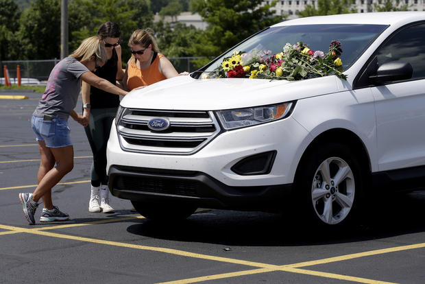 People pray next to a car believed to belong to a victim of a last night's duck boat accident
