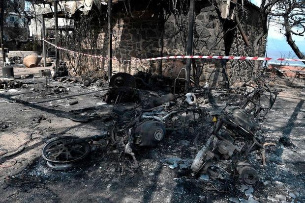Burnt out motorbikes and houses are cordoned off at the seaside resort of Mati