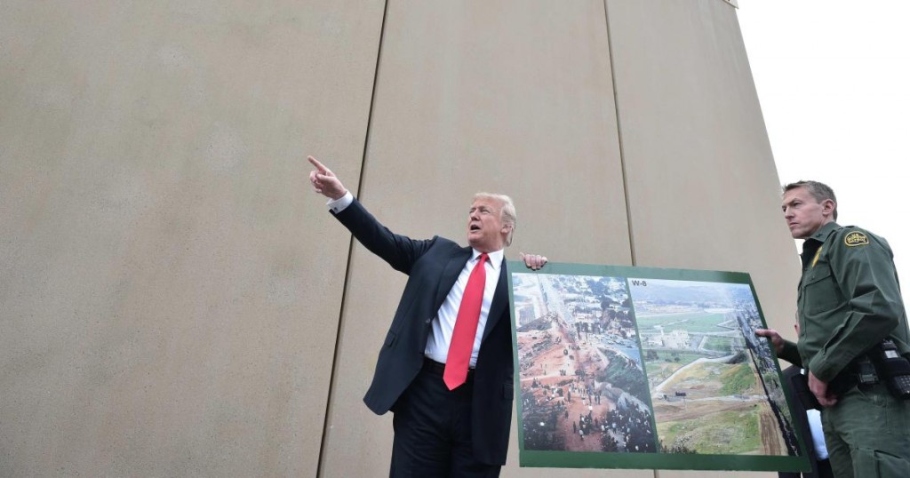 US President Donald Trump holds up a poster of before and after photos of a segment of the border wall prototypes with Chief Patrol Agent Rodney S. Scott (R) in San Diego