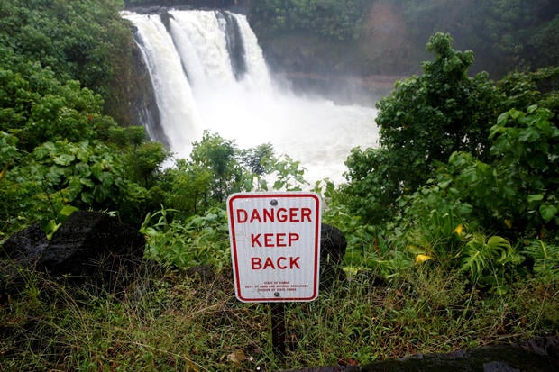 A sign warns of danger at a waterfall swollen by rain from Hurricane Lane in Hilo