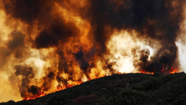 Wind-driven flames roll over a hill towards homes during the River Fire (Mendocino Complex) near Lakeport