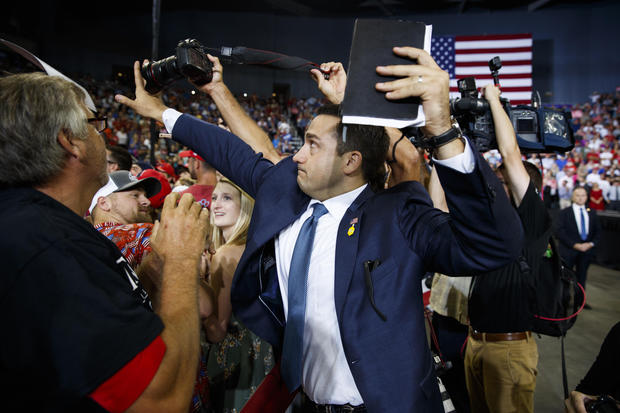 ADDS THAT MAN BLOCKING CAMERA IS A VOLUNTEER   - A volunteer member of the advance team for President Donald Trump blocks a camera as a photojournalist attempts to take a photo of a protester during a campaign rally at the Ford Center