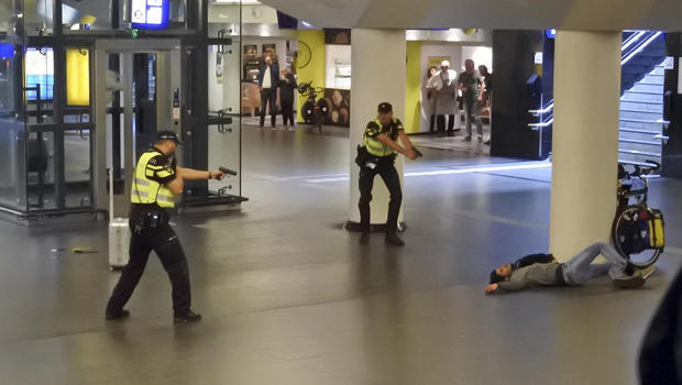 Dutch police officers point their guns at a wounded 19-year-old man who was shot by police after stabbing two people in the central railway station in Amsterdam