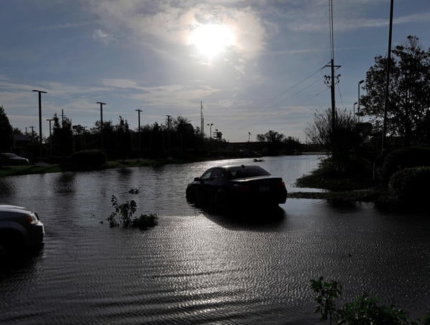 The sun reflects on flood water and stranded vehicles as it emerges after days of storm clouds and rain