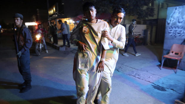 An injured boy is held up outside a hospital following a deadly attack in Kabul