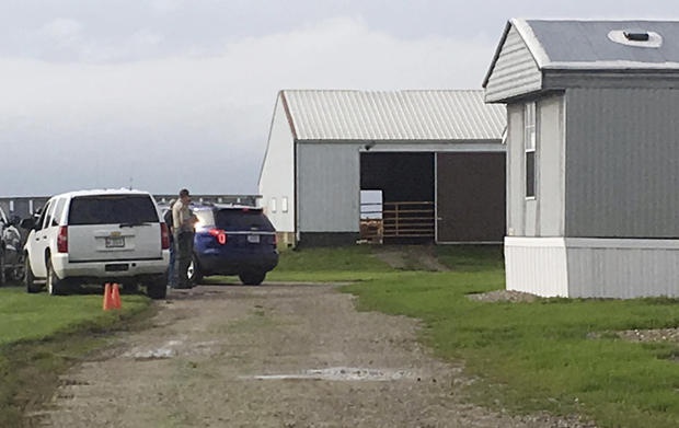 A deputy with the Poweshiek County sheriff's office stands on the property of Yarrabee Farms in Brooklyn
