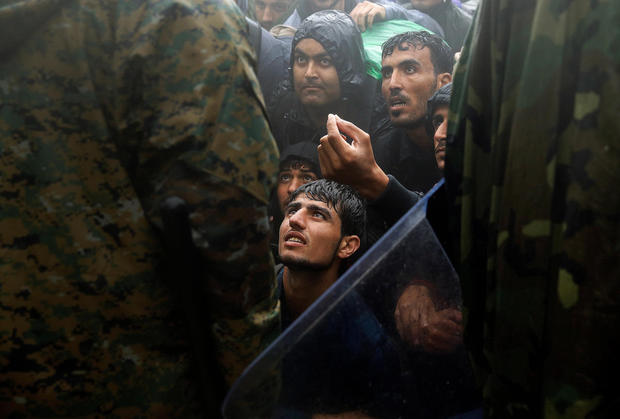 FILE PHOTO: Migrants and refugees beg Macedonian policemen to allow passage to cross the border from Greece into Macedonia during a rainstorm