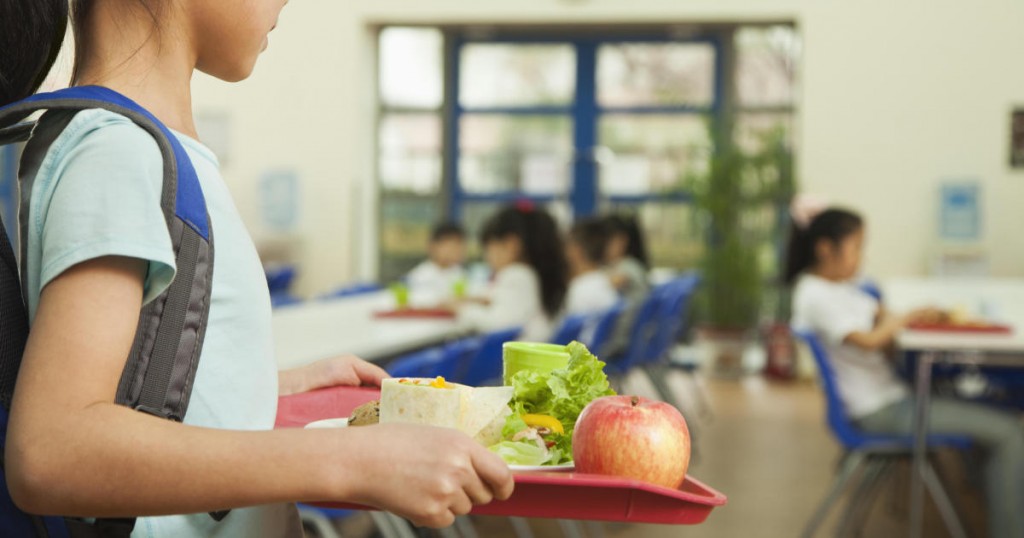 School girl holding food tray in school cafeteria