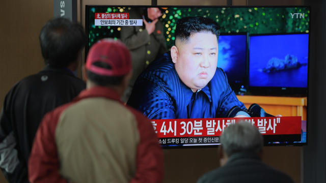 People watch a television news programme showing a picture of North Korean leader Kim Jong Un