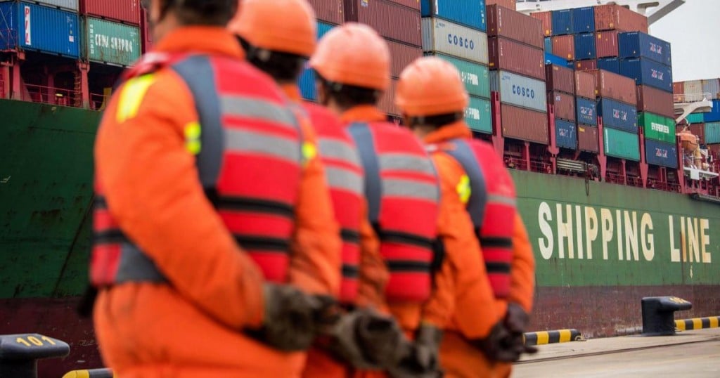 Employees look at a cargo ship at a port in Qingdao