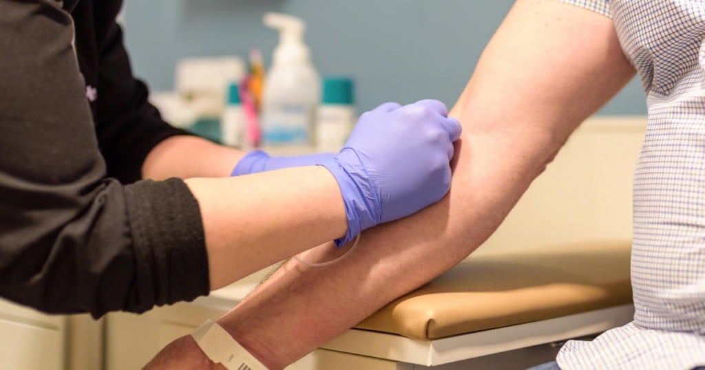 Adult man getting blood drawn in exam room by healthcare worker