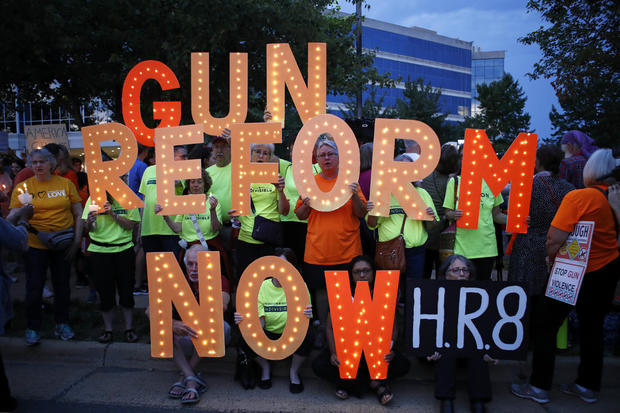 People gather at a vigil for recent victims of gun violence outside the National Rifle Association's headquarters building