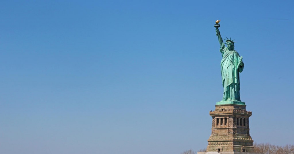 Horizontal image of Statue of Liberty. In front of it many people are queued for the visit
