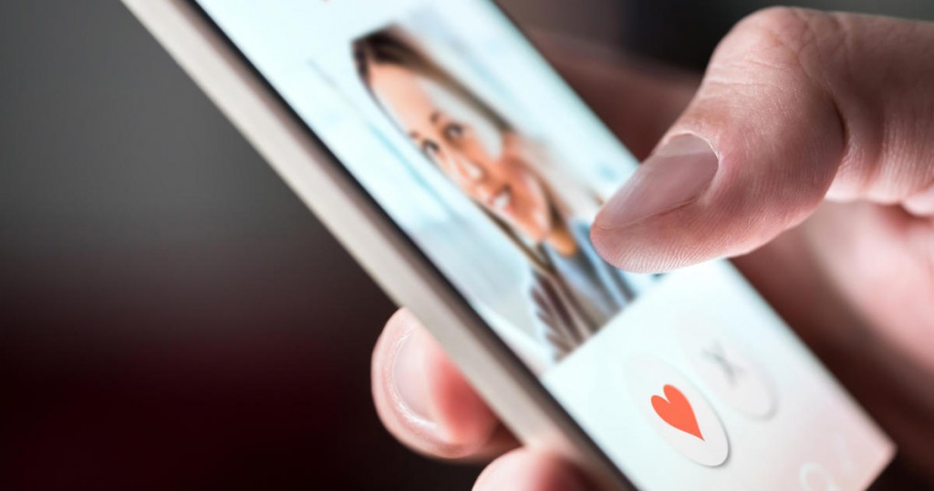 Online dating app in smartphone. Man looking at photo of beautiful woman. Person swiping and liking profiles on relationship site or application. Single guy searching for love partner. Mockup website.