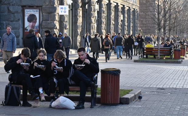 Young people have a snack outside a cafe during a typically warm winter day in the center of the Ukrainian capital Kiev on December 18