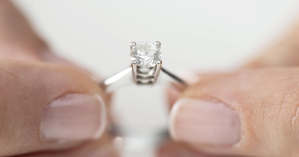 Hands holding diamond ring.