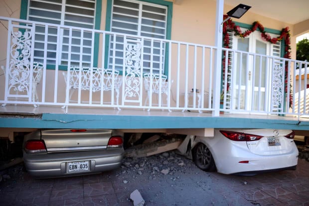 Cars are crushed under a home that collapsed after an earthquake hit Guanica