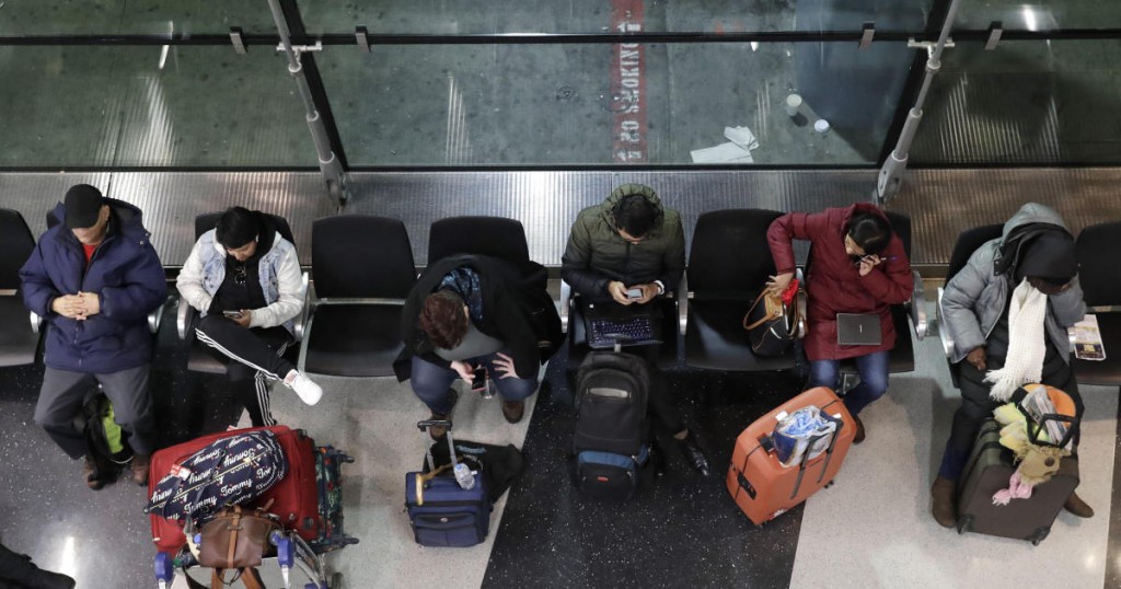 Travelers sit as they wait for their flight at O'Hare airport in Chicago