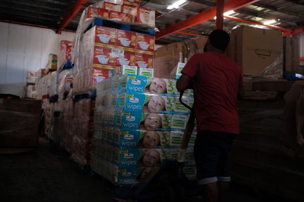 A man removes diapers and baby wipes from a warehouse filled with supplies