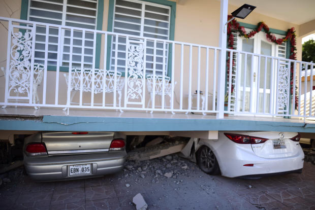 Cars are crushed under a home that collapsed after an earthquake hit Guanica