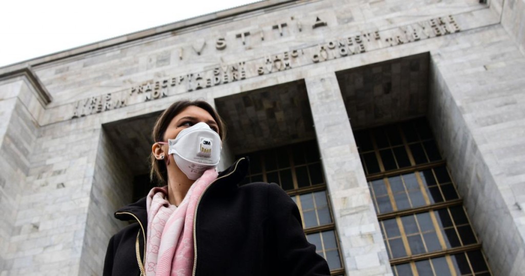 A woman wearing a respiratory mask exits from the Palace of Justice in Milan
