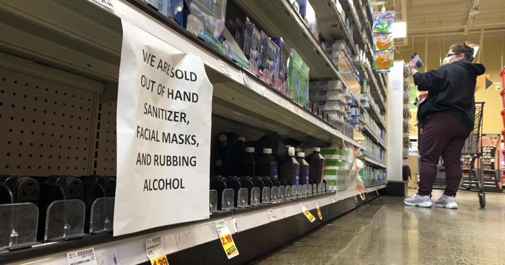 A shopper wearing a mask is pictured near a sign advising out-of-stock sanitizer