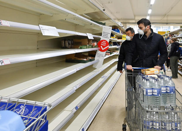 Shoppers wearing masks are faced with partially empty shelves at a supermarket in London on March 14