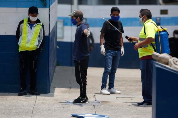 A man is disinfected by a health worker at the site where Guatemalans returned from the U.S. are being held in Guatemala City