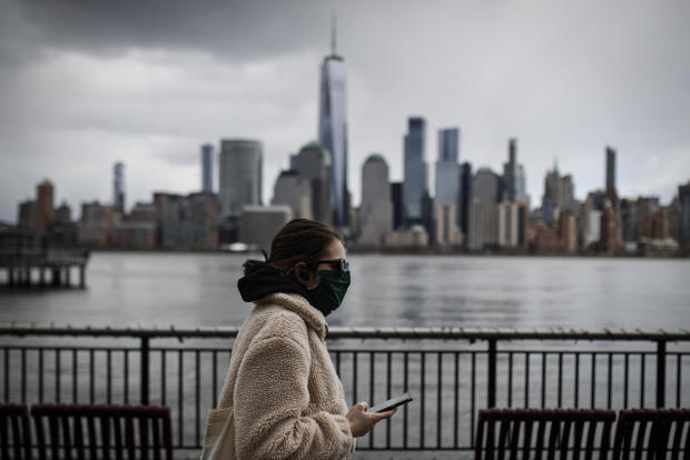 The downtown New York City skyline looms over pedestrians wearing masks due to COVID-19 concerns