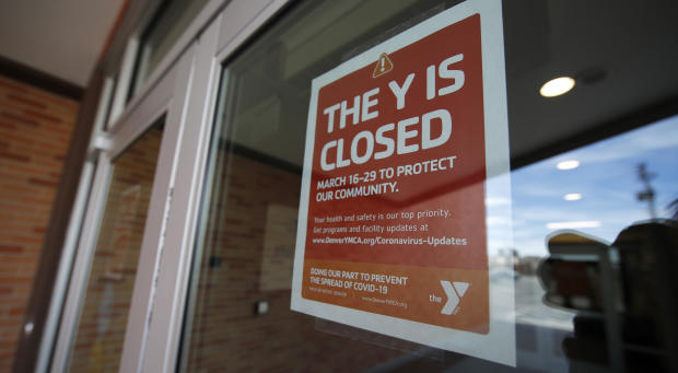 A sign hangs on the door to the Schlessmann YMCA as gyms have been forced to close in Colorado's efforts to fend off the spread of coronavirus Monday