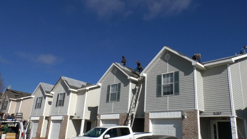 Roofing company laying tarp for storm damage victims