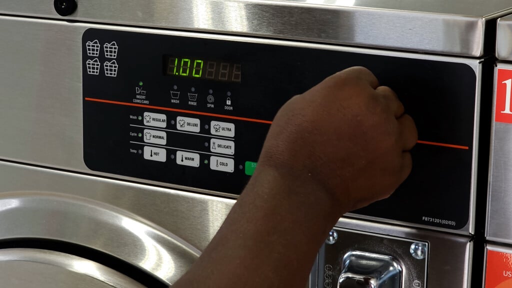 Hand Putting Coin In Laundry