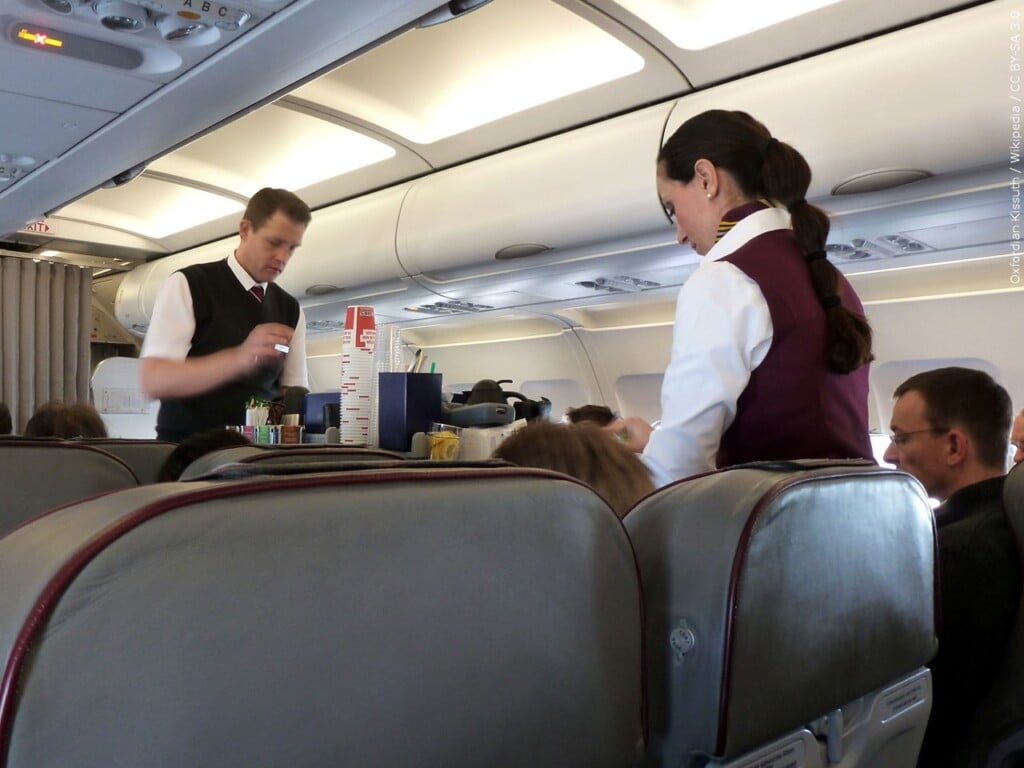 Flight attendants serving beverages and snacks on a plane