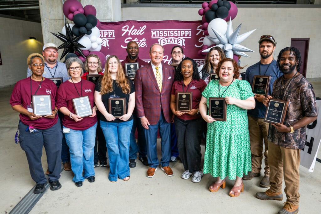A dozen MSU staff are being recognized with 2026 Zacharias Distinguished Staff Awards for exemplary work in their roles at the university. Being congratulated by MSU President Mark E. Keenum, center, are, front row, from left, Donna Reese, MaryAnn Latham, Tracy Wilcox, (Keenum), Rhonda Hannah, Delaney Foster and Brentson Hall; back row, from left, Mark Hall, Paige White, Alexis Hamilton, Brittany Adams, Ashlee Reed and Zack Ivy. (Photo by Grace Cockrell)