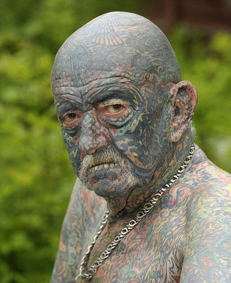 An elderly man with a full face tattoo.