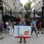 Artist Kaya Mar protests with a picture at the gate of Downing Street in London