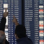 Two men point toward plane arrivals on a flight information board at San Francisco International Airport in San Francisco, Tuesday, Nov. 26, 2019. Northern California and southern Oregon residents are bracing for a 'bomb cyclone' that's expected at one of the busiest travel times of the year.