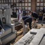A Priest And Relatives Pray As A Victim Of The Covid 19 Is Buried By Undertakers At The Almudena Cemetery In Madrid, Spain, March 28, 2020