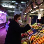 A Woman Wearing A Face Mask And Gloves Protection Against Coronavirus Buys Vegetables In A Municipal Market In Madrid, Spain, Saturday, March 28, 2020