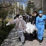 People Wearing Protective Clothing Carry The Body Of A Victim Who Died After Being Infected With The New Coronavirus At A Cemetery Just Outside Tehran, Iran, March 30, 2020.