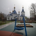 A Caution Tape Cordons Off An Empty Children's Playground With An Orthodox Church Seen In The Background